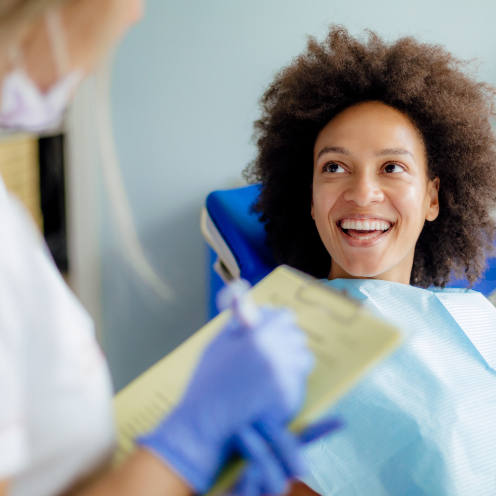 A woman is smiling while sitting in a dental chair