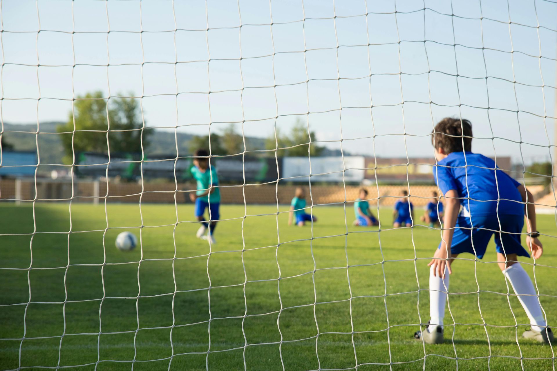 Photo of kids playing soccer, one kid is preparing for a penalty shot and another kid is defending