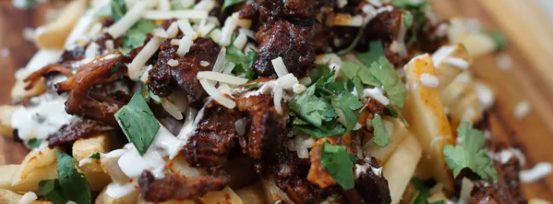 Slow-smoked birria fries topped with shredded beef, cheese, and fresh cilantro on a Big Green Egg