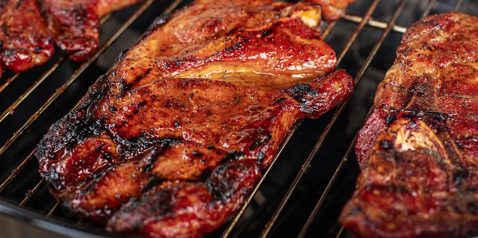 Flame-seared St. Louis style pork steaks glazed with barbecue sauce on a drum smoker