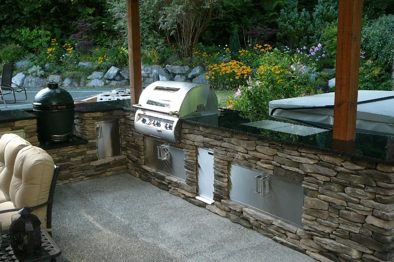 Custom outdoor kitchen with built-in grill and stone cabinetry designed for backyard entertaining