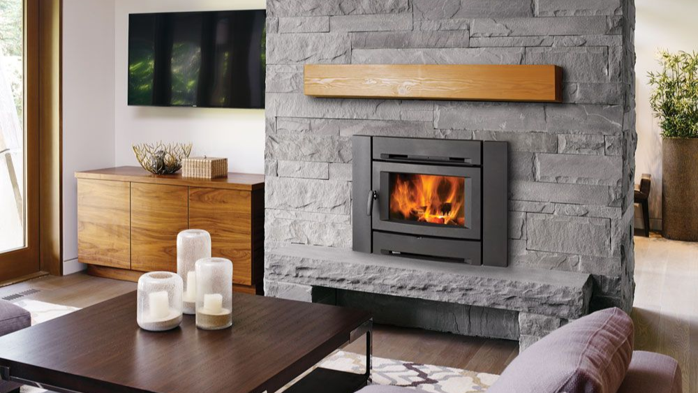 Wood fireplace insert installed in a masonry fireplace with timber mantel and radiant heat display.