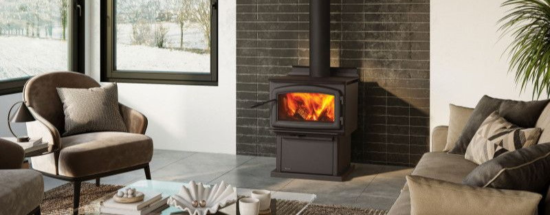 Wood stove burning in a modern living room with large windows