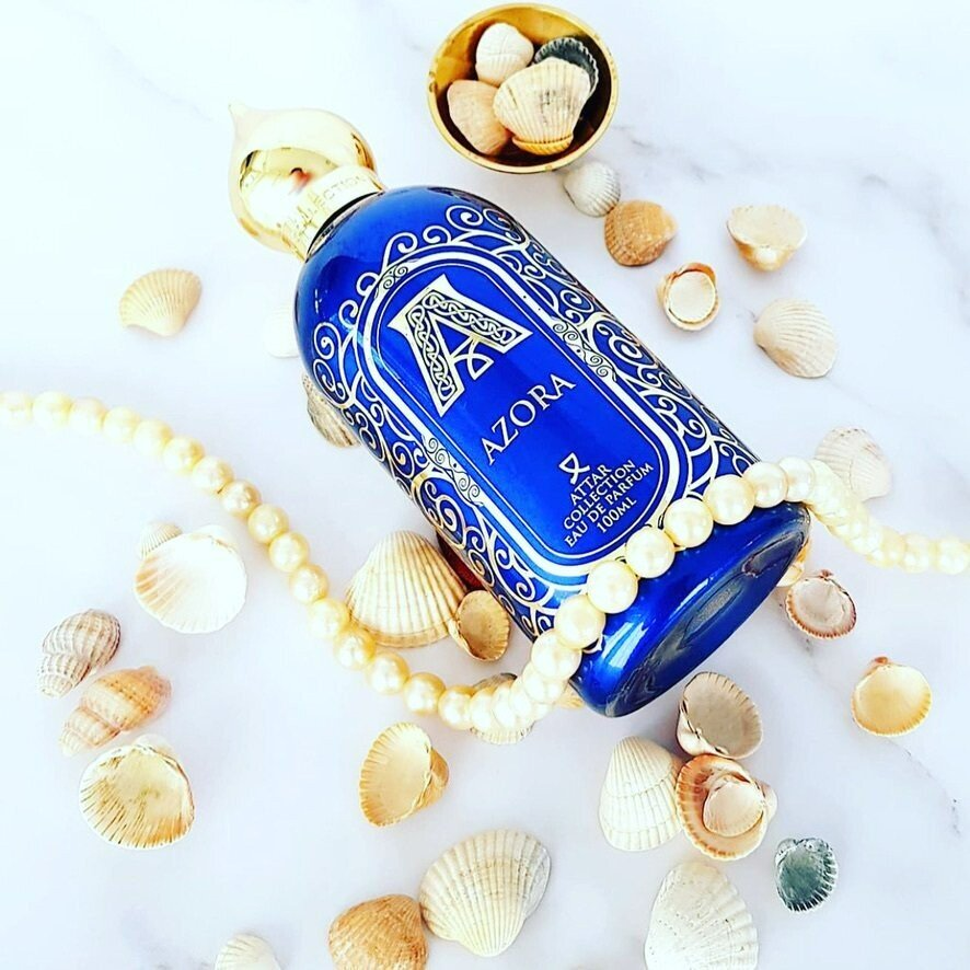 A blue bottle of azora surrounded by seashells and pearls