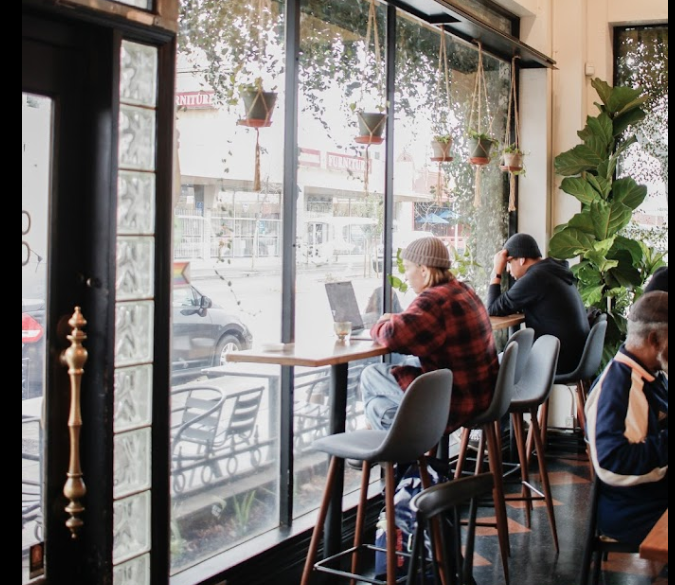 A group of people are sitting at tables in a restaurant looking out the window.