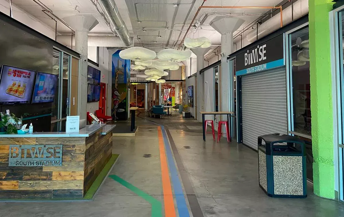 A long hallway in a building with a counter and a trash can.
