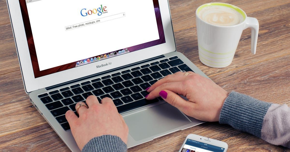 A person is typing on a laptop with a cup of coffee in the background.