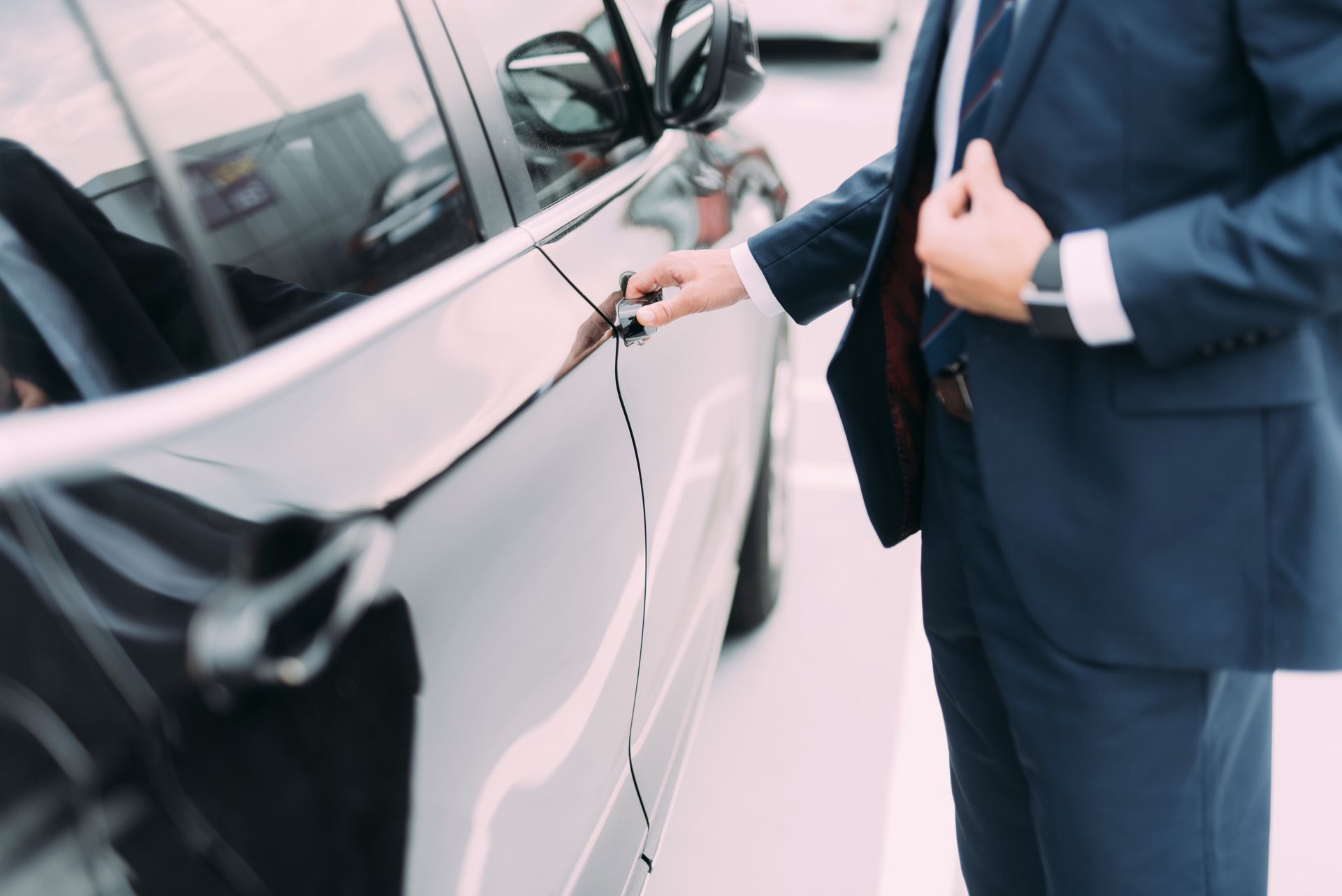 Man in a suit opening a car door.