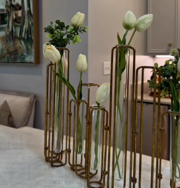 White tulips in tall gold vases on a table in a modern living room