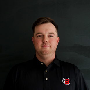 Man in a black polo shirt standing against a dark background