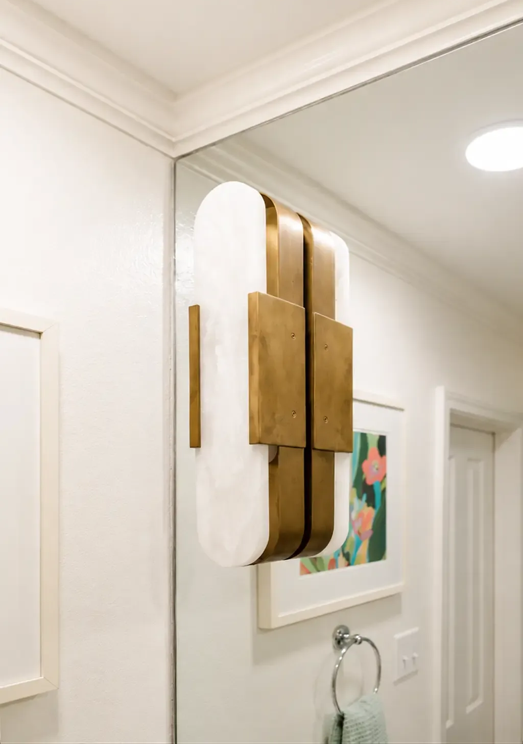 Wooden wall sconce with white shade in a bright hallway above a framed print