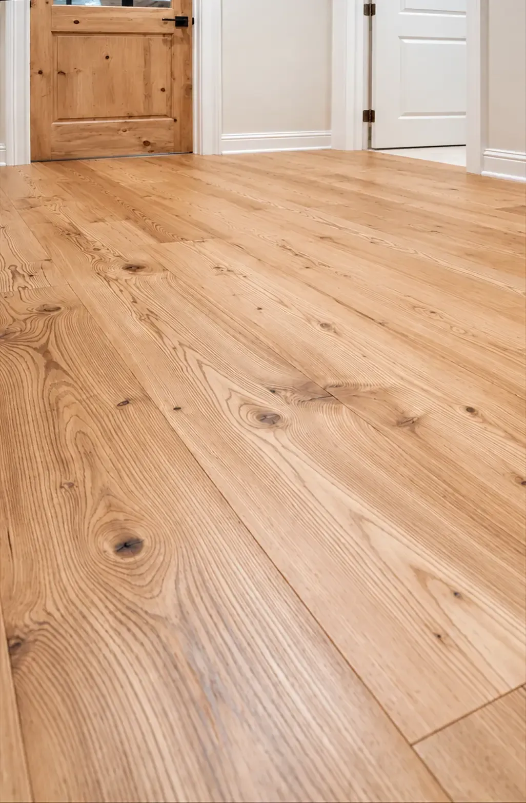 Light oak wood floor in a bright room with white doors and a wooden cabinet.