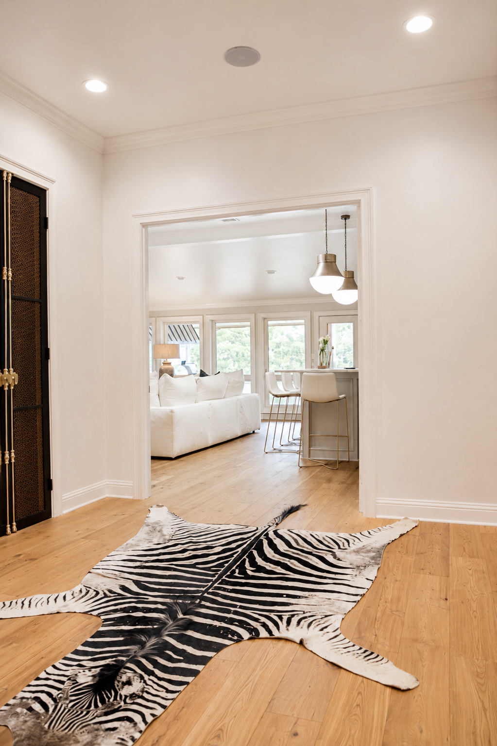 Hallway with zebra hide rug leading to a bright white bedroom and desk area