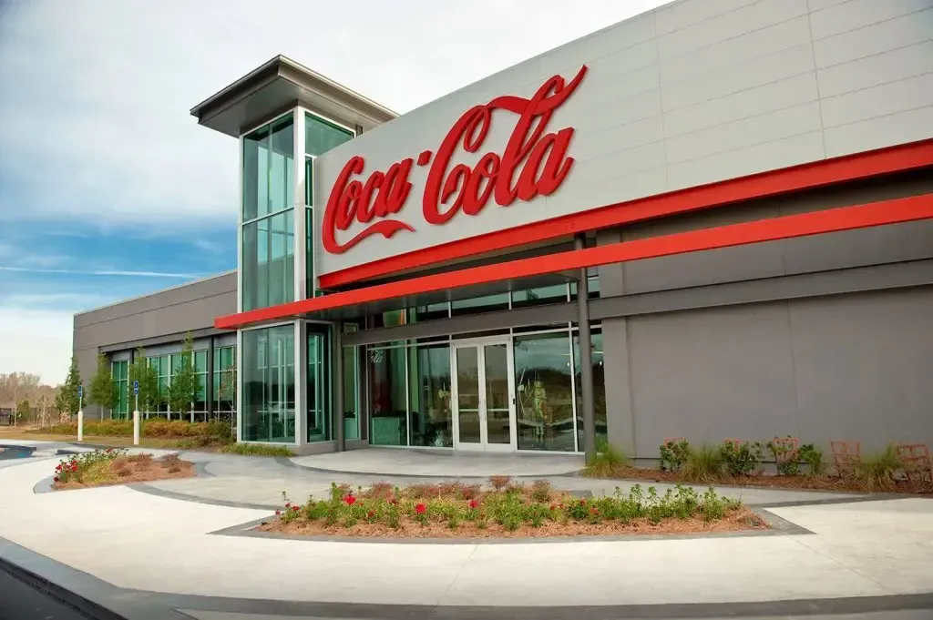 Coca-Cola office building exterior with red logo and glass entrance under a clear sky