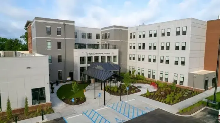 Modern campus courtyard with multi-story buildings, a covered walkway, and landscaped garden beds