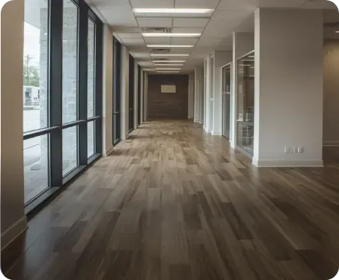 Empty modern hallway with large windows, wood flooring, and ceiling lights