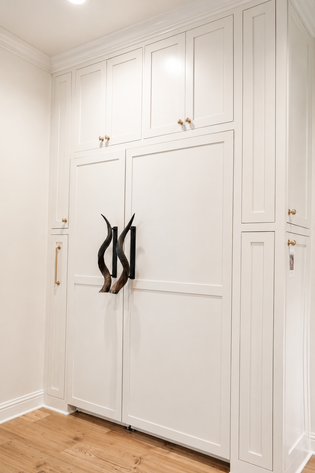 White built-in closet cabinets with black handles in a bright room and wood floor