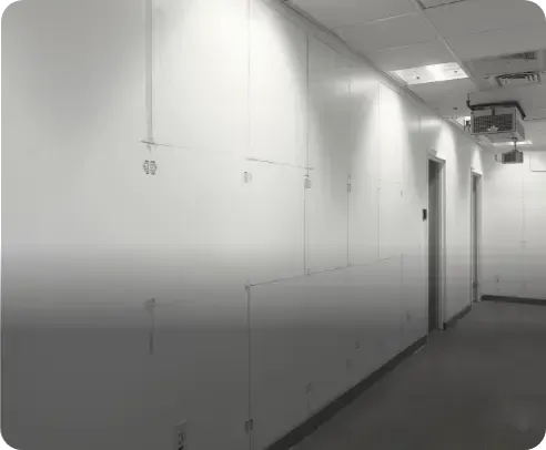 Empty white hallway with closed doors and overhead lights in a building corridor