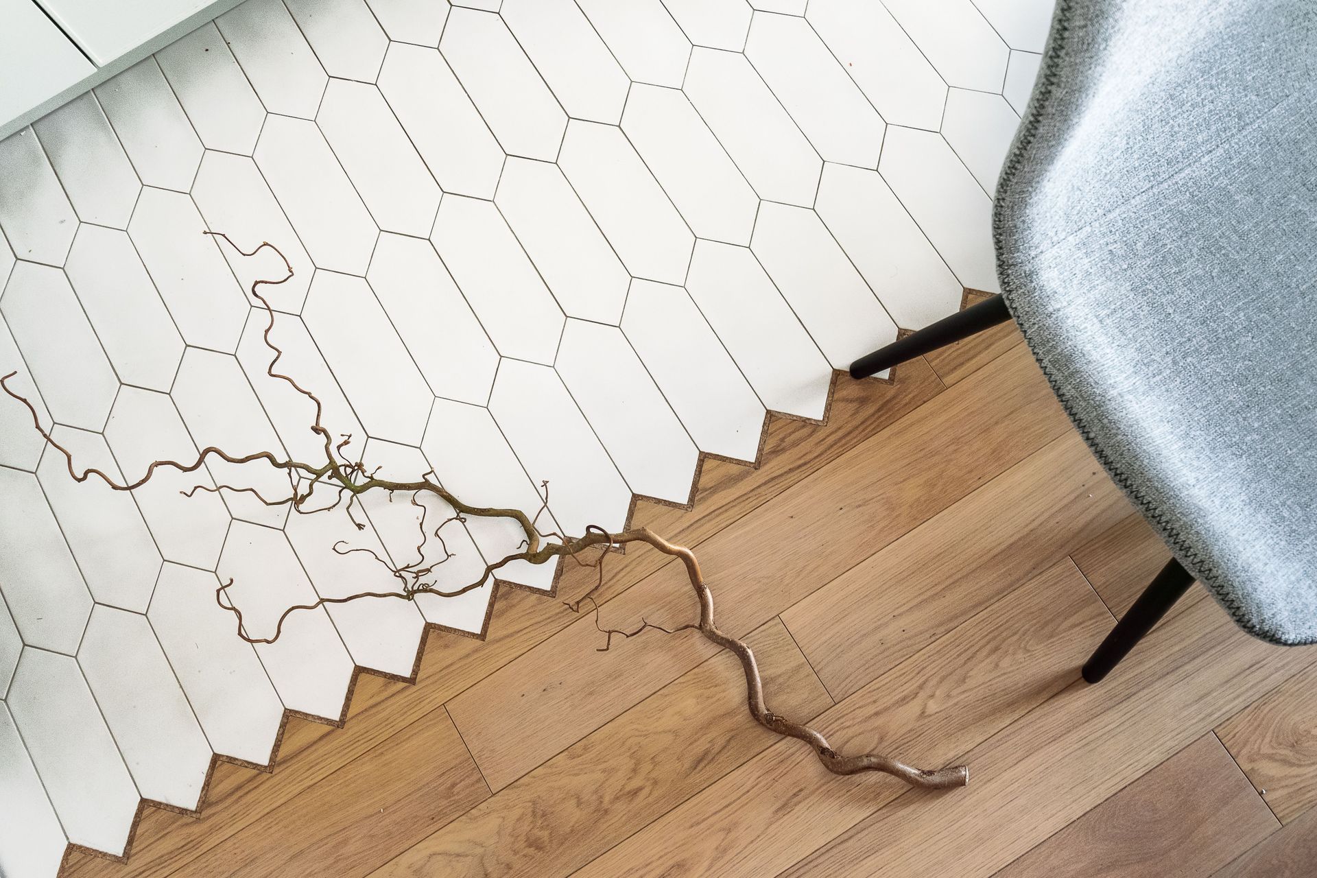 Knotted cord lying on a white hexagon rug beside a wooden floor and gray chair leg