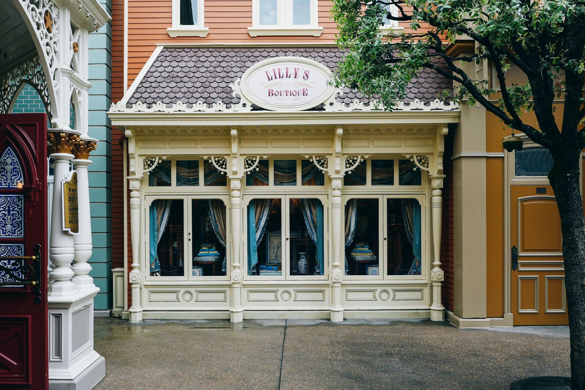 Pastel storefront with white trim and hanging plants on a cobblestone street