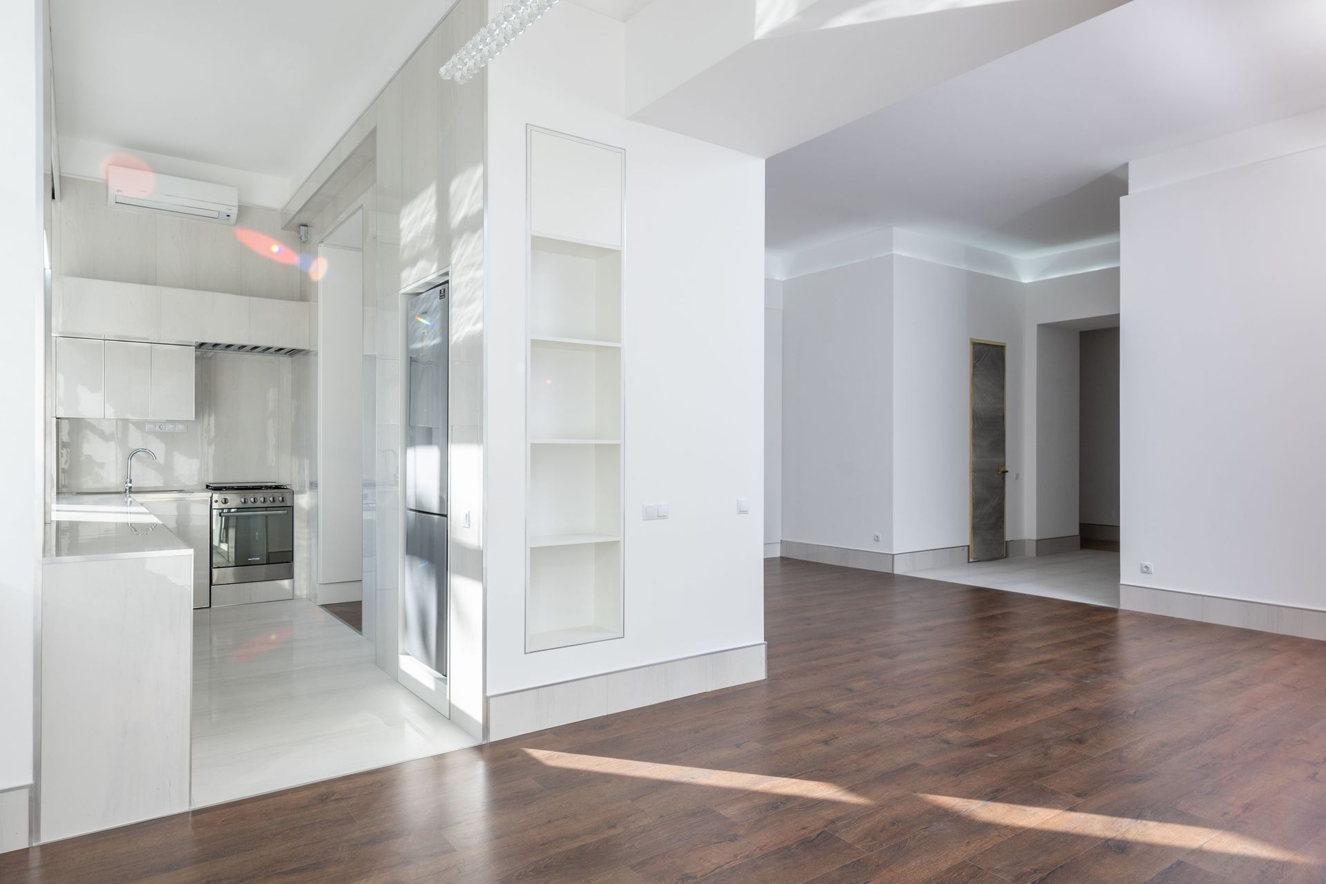 Bright empty modern apartment interior with white kitchen and hardwood floors