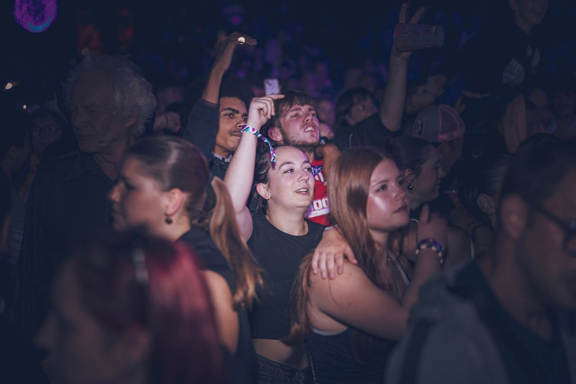 Piste de danse bondée d'une boîte de nuit, les mains levées sous une faible lumière violette