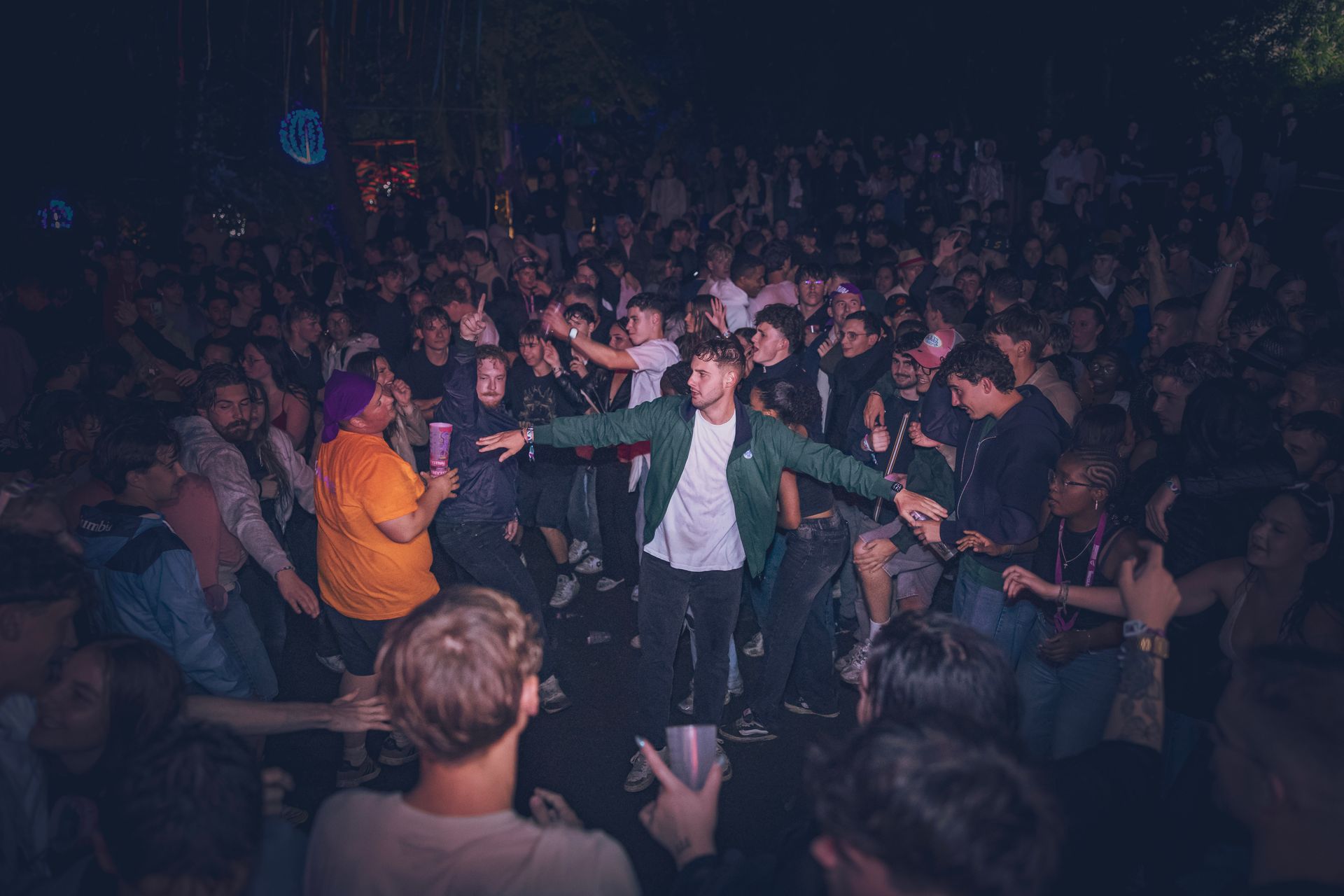 Foule à un concert avec un artiste en veste verte tendant la main vers le public