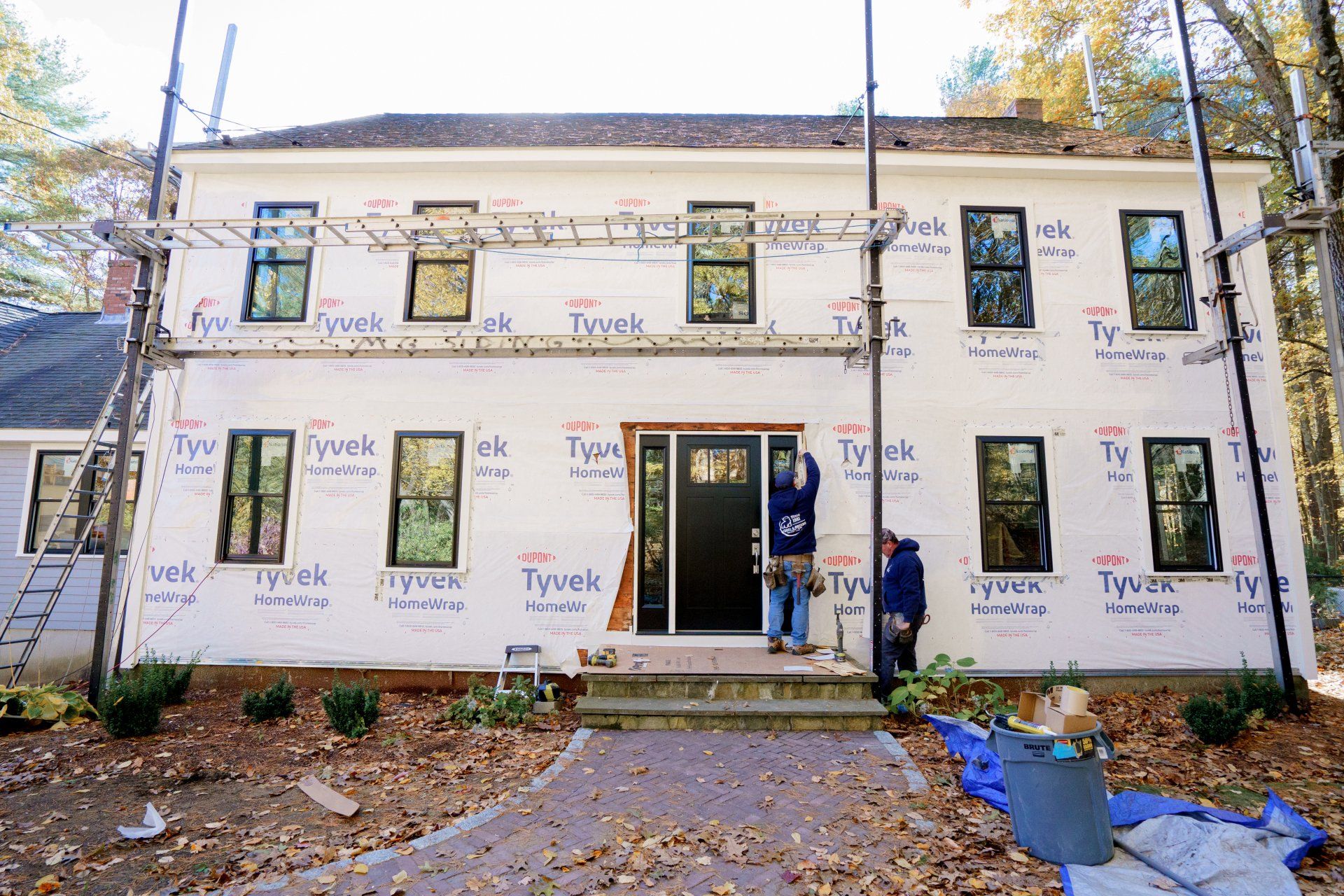 A man is standing in front of a house that is being remodeled.