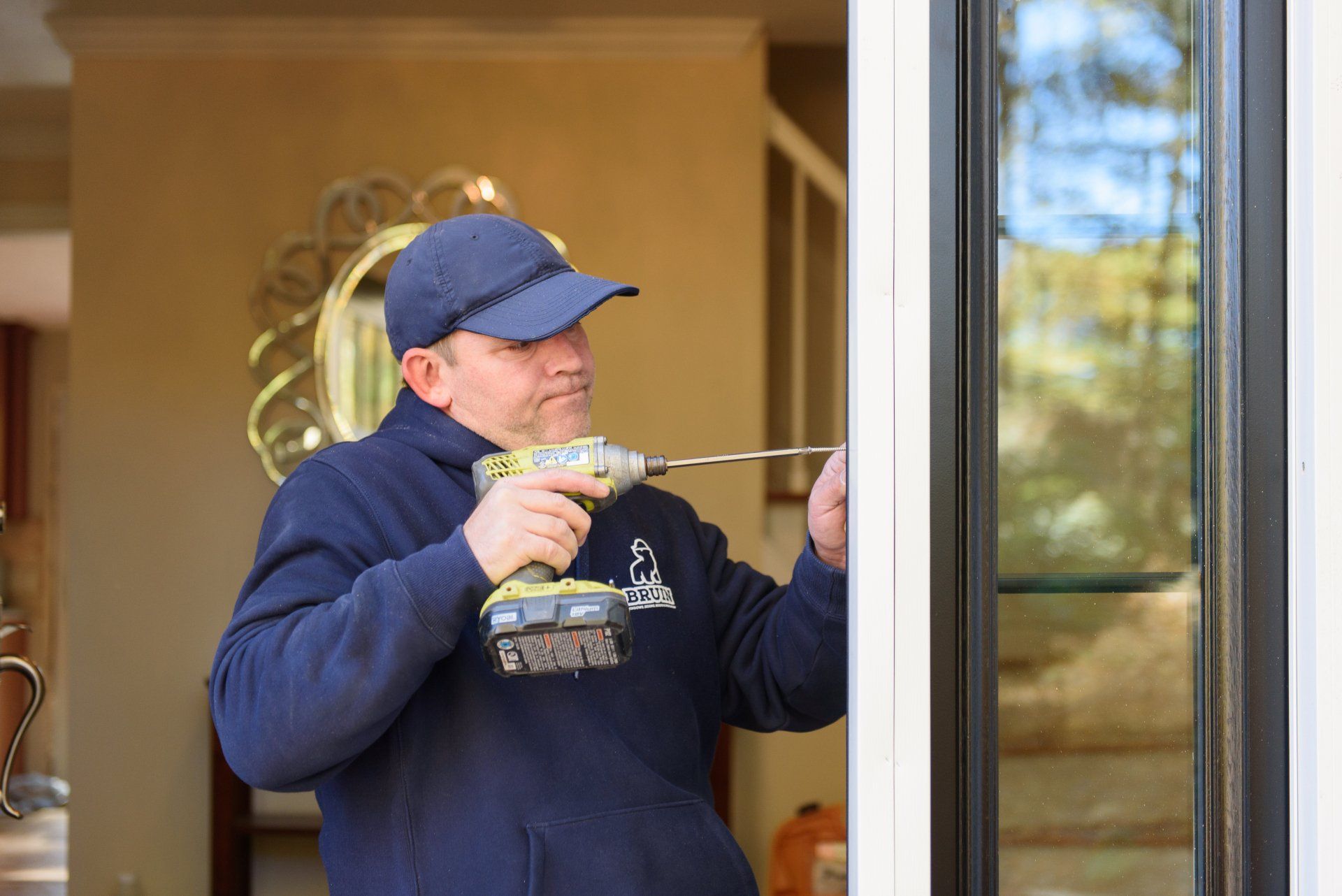 A man is using a drill to fix a door.