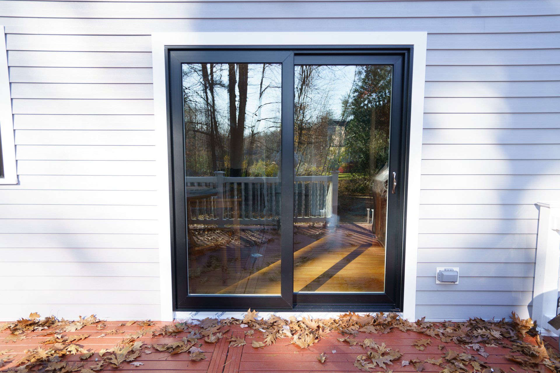 A sliding glass door on the side of a house leading to a deck.