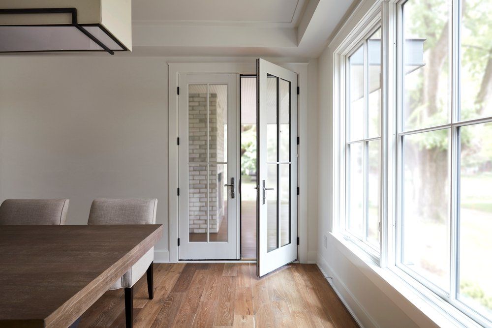 A dining room with a table and chairs and a large window
