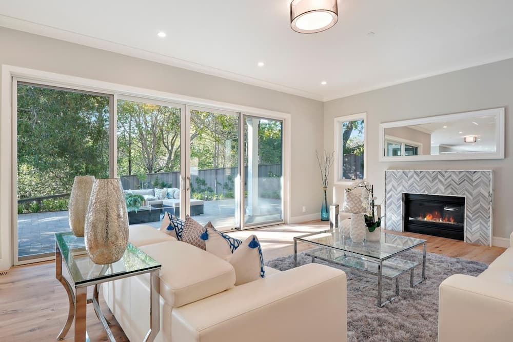 A living room with a couch , chair , coffee table , fireplace and sliding glass doors.