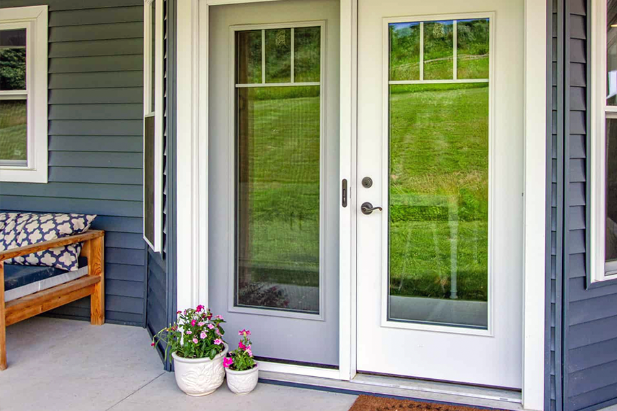 There is a porch with a bench and flowers in front of the door.