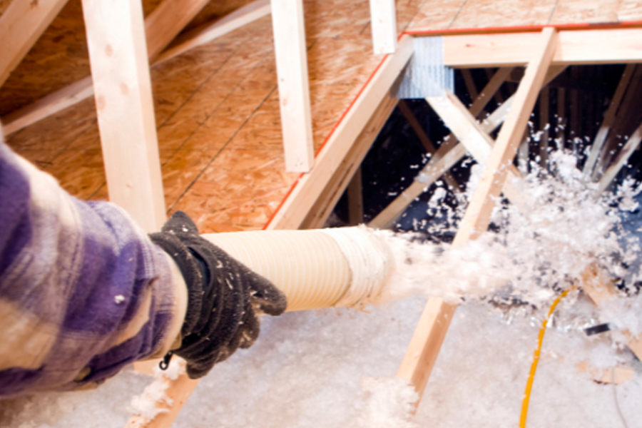 A person is blowing insulation into an attic