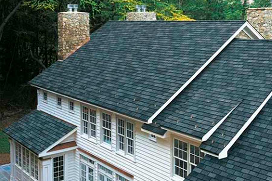 A large white house with a black roof and chimneys.