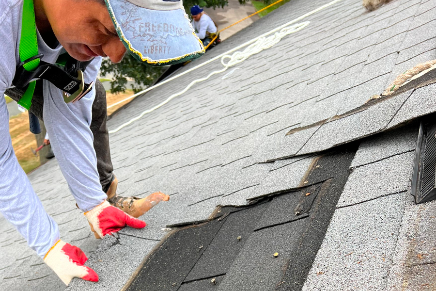 A man wearing red gloves is working on a roof.