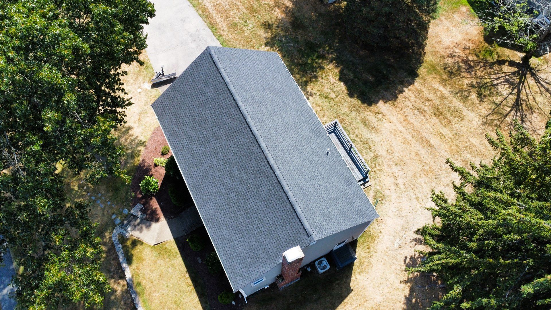 An aerial view of a house with a black roof surrounded by trees.