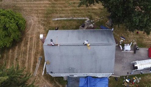 An aerial view of a house with a roof being repaired.