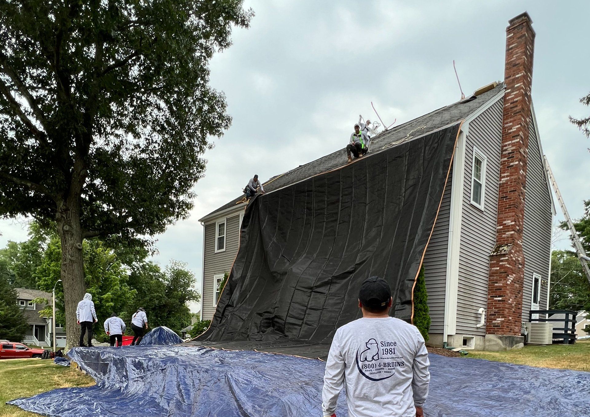 A man is standing in front of a house with a tarp on it.