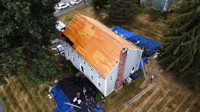 An aerial view of a house with a wooden roof being installed.
