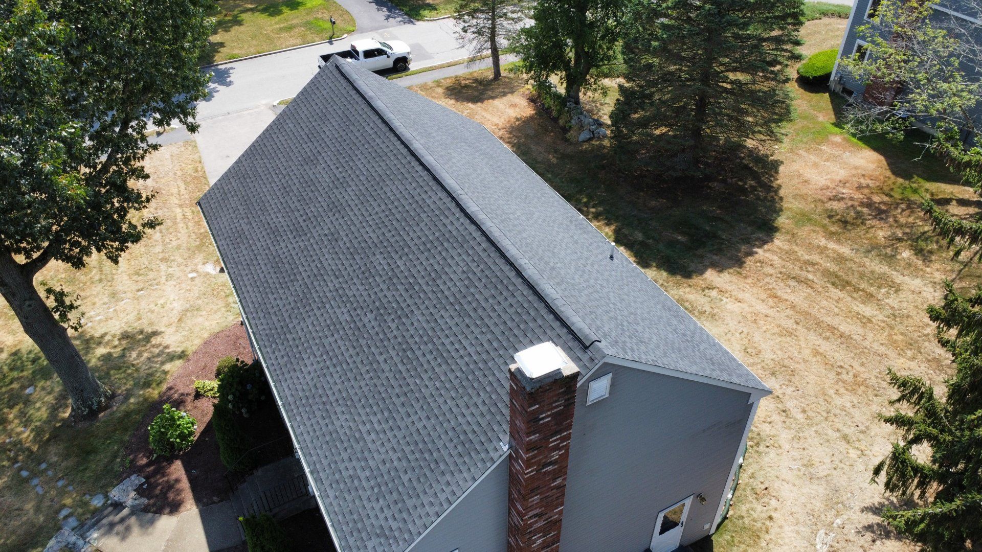 An aerial view of a house with a black roof and a chimney.
