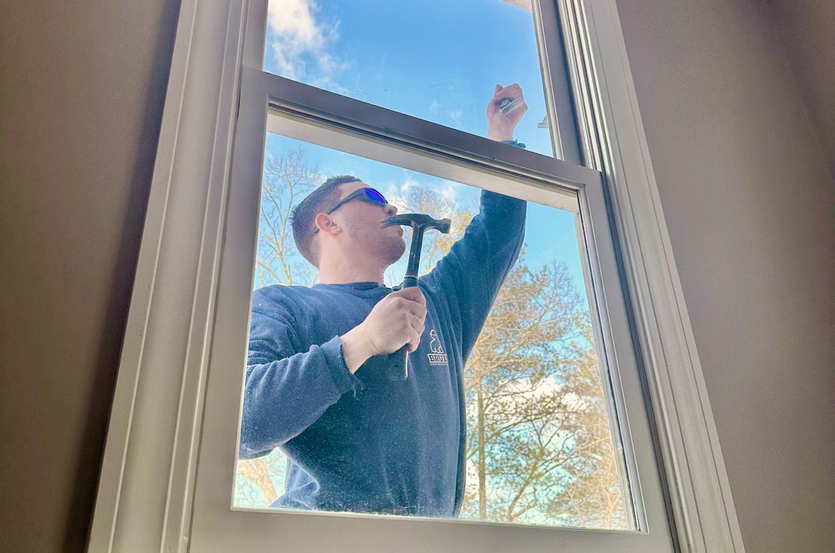 Person cleaning a window from outside with a squeegee, seen through the glass.