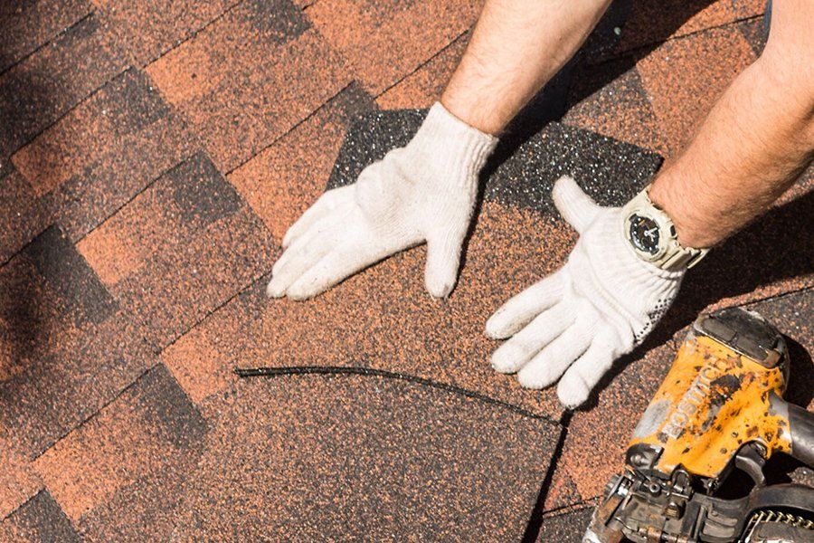 A man wearing white gloves is working on a roof.