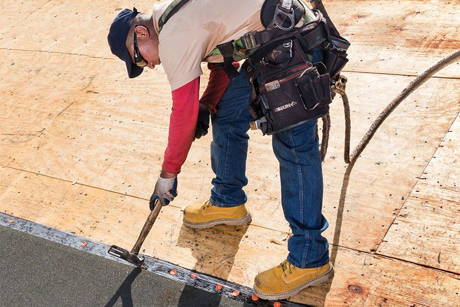 A man is working on a roof with a tool.