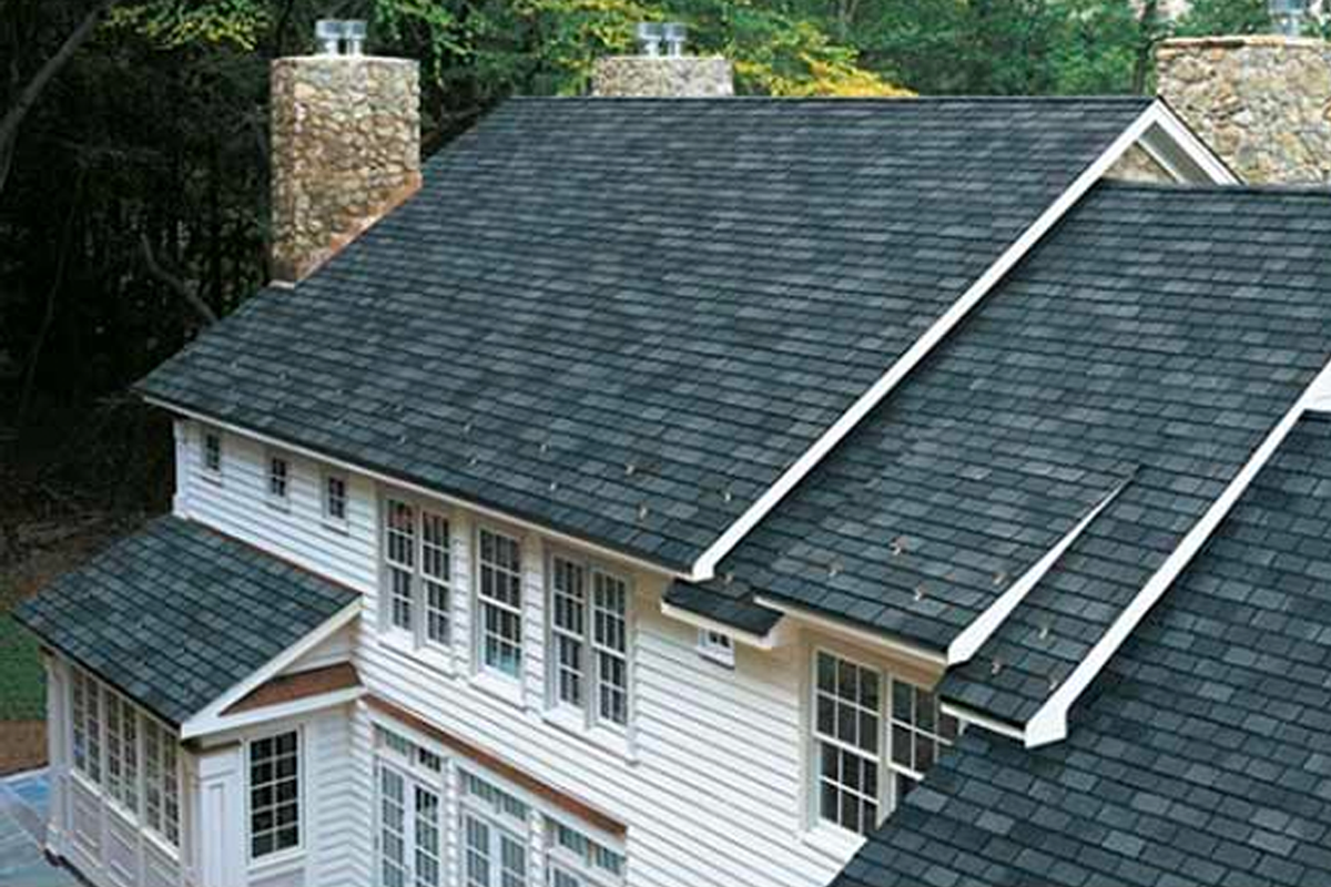 An aerial view of a large white house with a black roof.