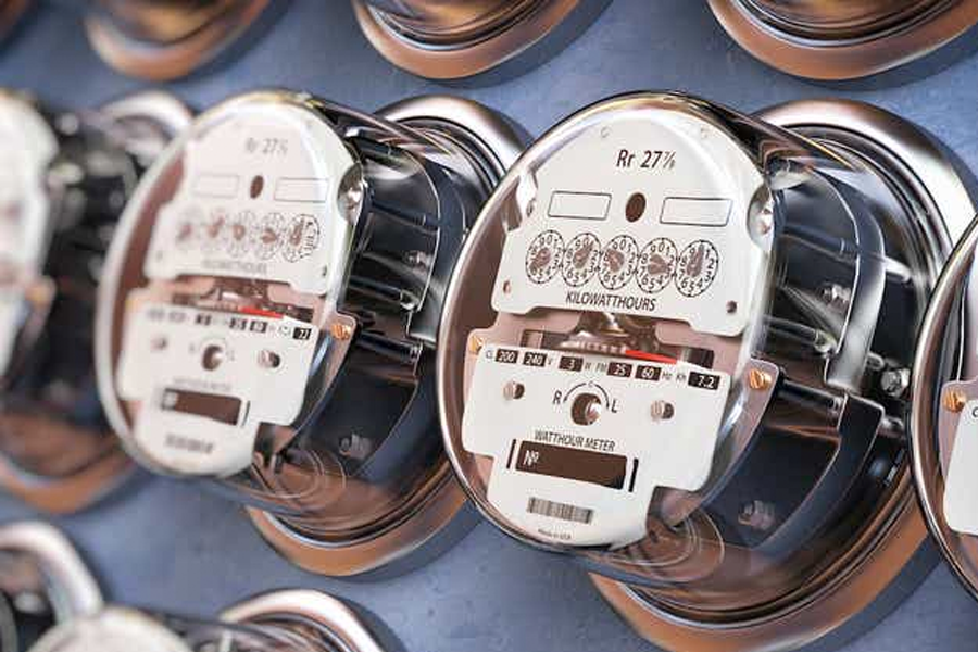 A bunch of electric meters are lined up on a wall.