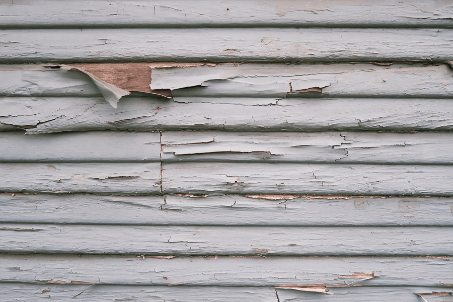 A close up of a wooden wall with peeling paint.