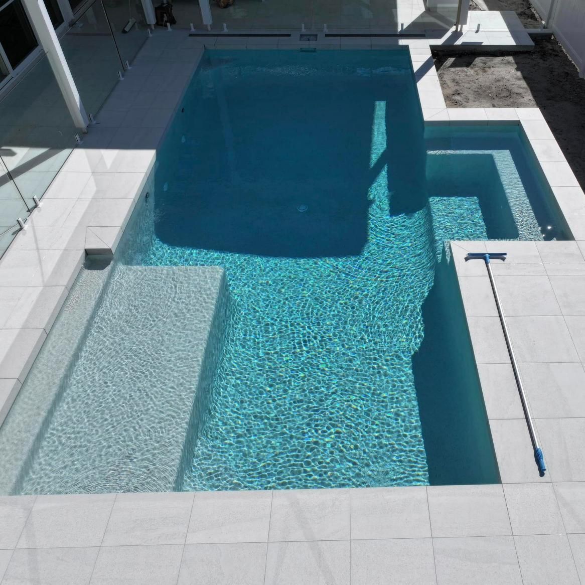 A Large Swimming Pool With Stairs and a Broom — Pools By Design in Gympie, QLD