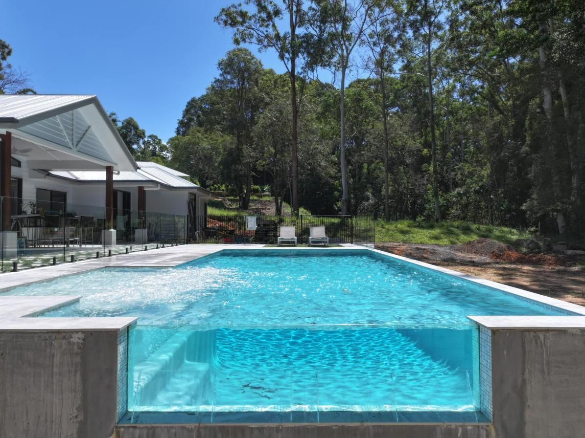 A Large Swimming Pool Surrounded by Trees and a House — Pools By Design in Sunshine Coast Hinterland, QLD