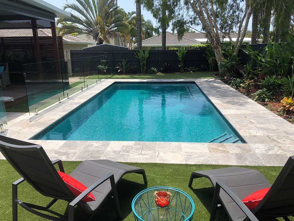 A Large Swimming Pool is Surrounded by Chairs and a Table — Pools By Design in Warana, QLD
